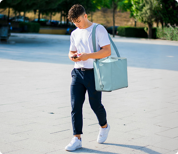A person carrying the Fello bag over their shoulder outdoors