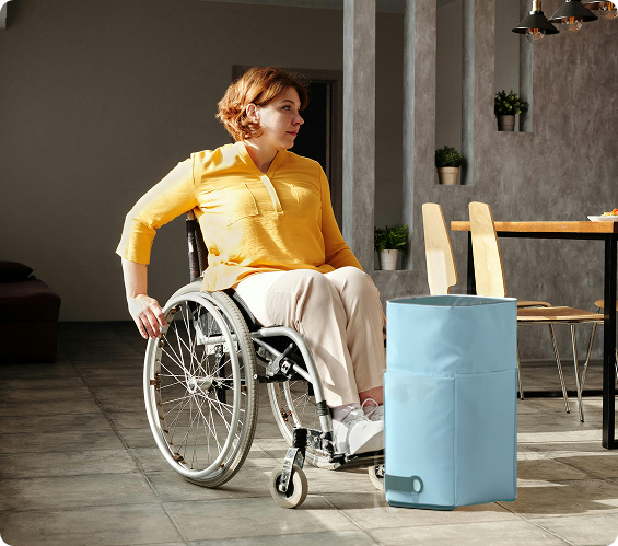 A wheelchair user beside the Fello laundry transport system in a dining room