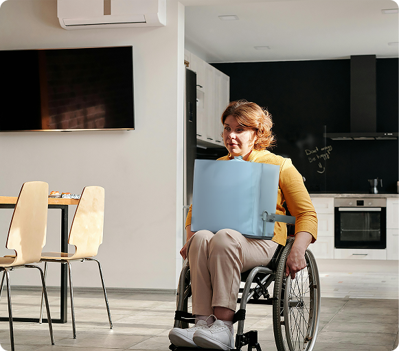A wheelchair user carrying the Fello bag on their lap through a kitchen